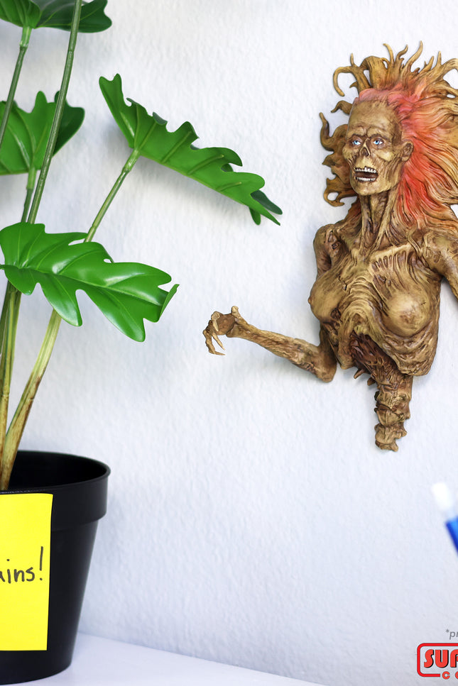 Half-Corpse Status hung on a white wall, shown with a vase with a sticky note that says "# more brains!"