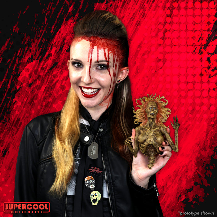 A female model with blood makeup holding a half-corpse figure, smiling at the camera.