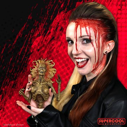 A female model with blood makeup holding a half-corpse figure, smiling at the camera.