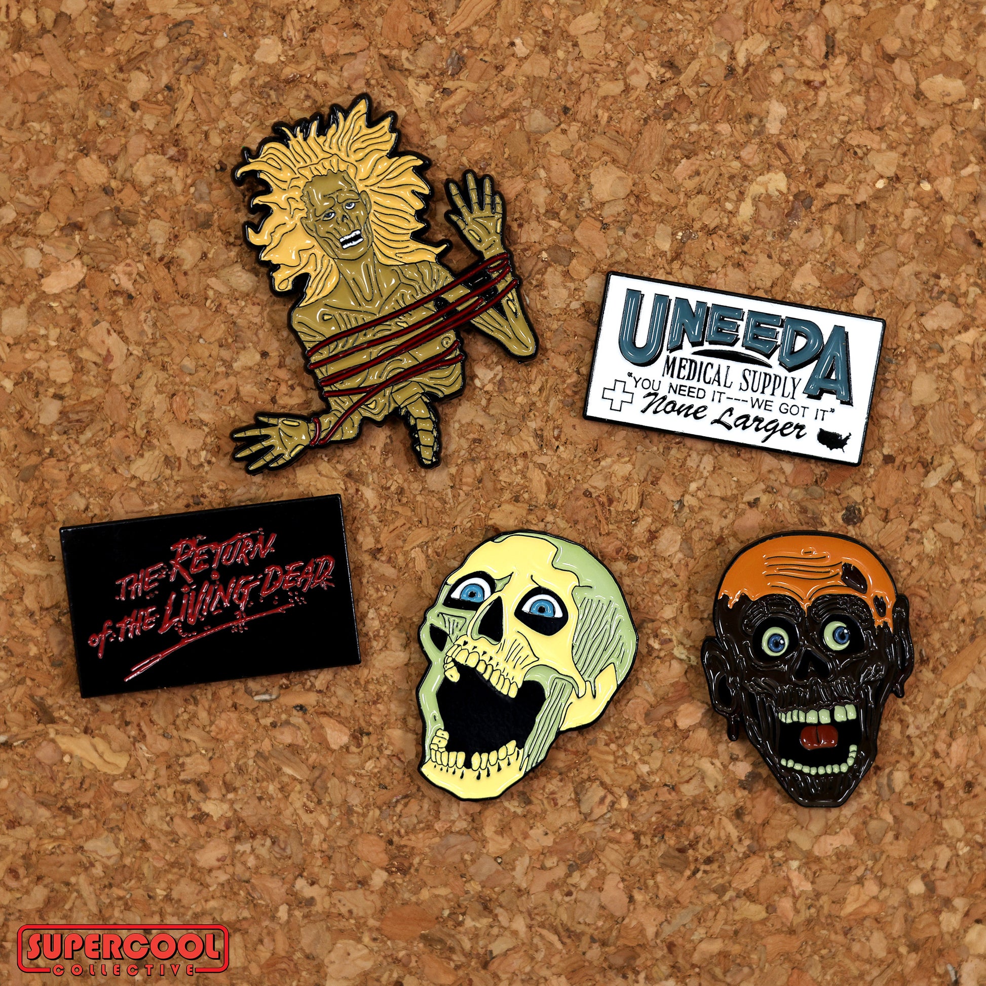 Top view of the Return of the Living Dead enamel pins featuring the skeleton head, Tarman head, Half-corpse, Uneeda Medical Supply logo, and The Return of The Living Dead Logo.